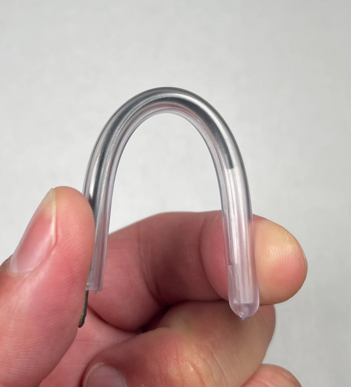 A clear flexible safety pen bent into a tight curve by hand